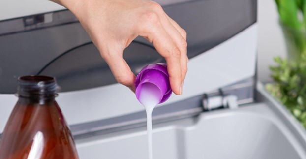 pouring fabric softener into washer